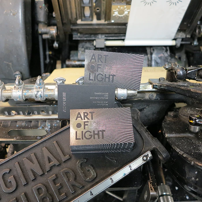 Visitkort tryckt med blank silverfolieprägling på ett matt svart papper Fuego coal black (500 gram) med texten Art of Light.